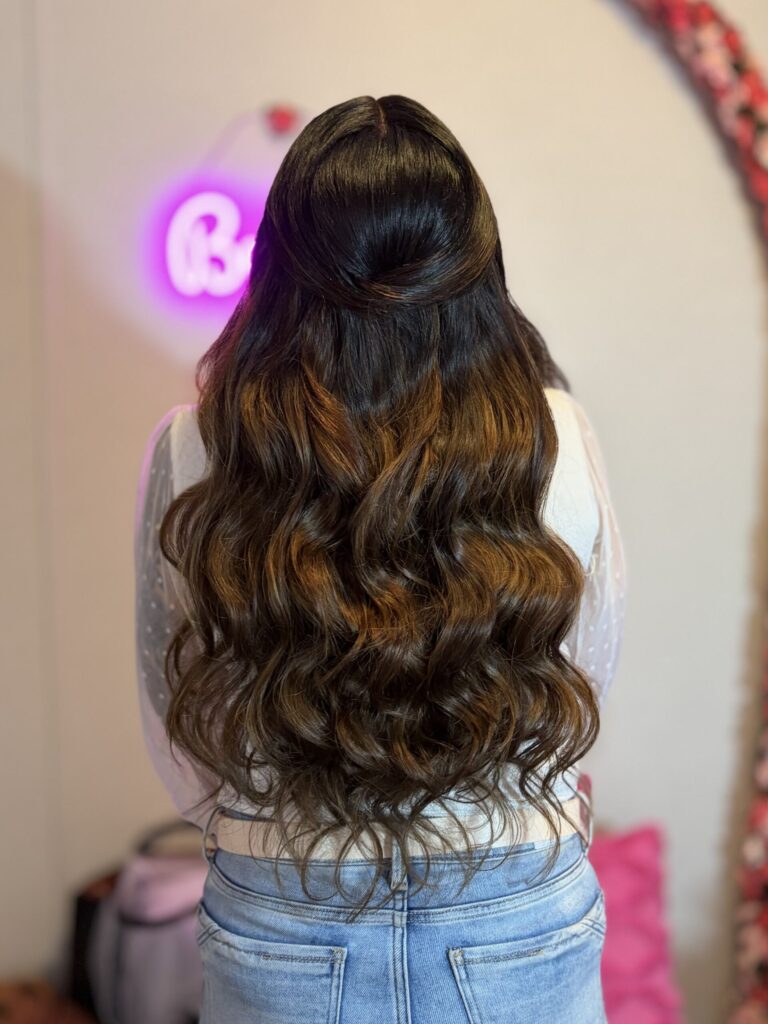 Brunette bridal model with a half-up half-down style featuring loose wavy curls and a twisted feature along the crown. 