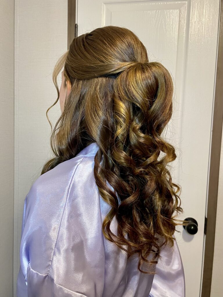 Brunette bridal party memeber with a half-up half-down style featuring loose wavy curls and a twisted feature along the crown, and face framing. Styled by Jaya R at the Belleza home studio. 