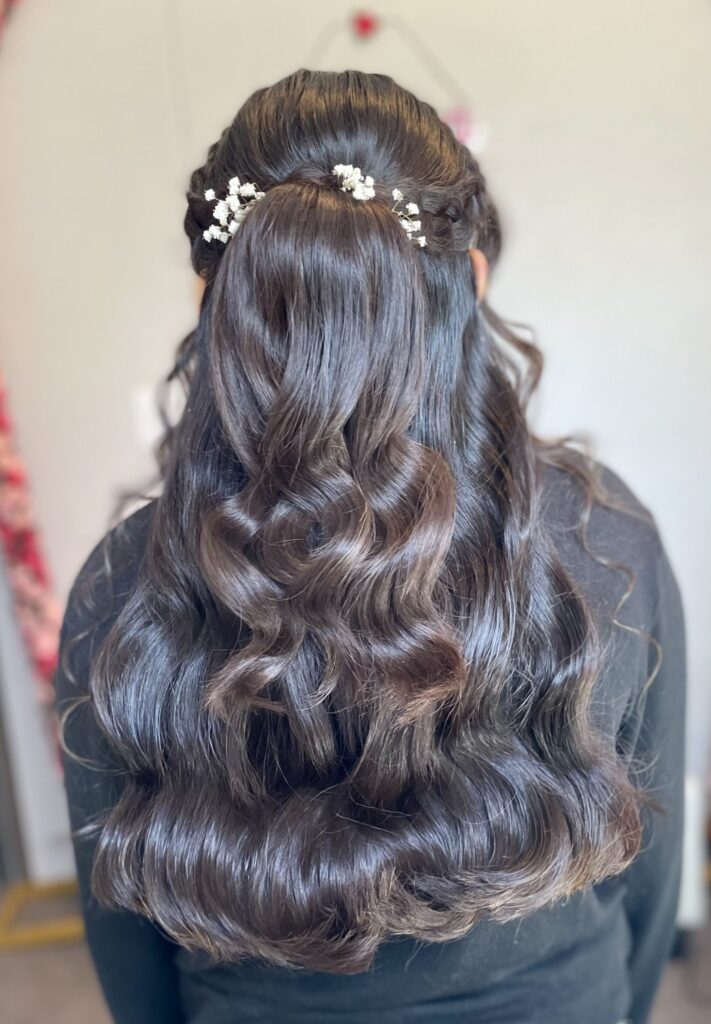 Bridal model from behind with romantic long black curled hair. Hair is in a half-up half-down style with baby's breath flowers. Hair styled in Ann Arbor Michigan, by Jaya Ronquillo at the Belleza Bridal Studio.