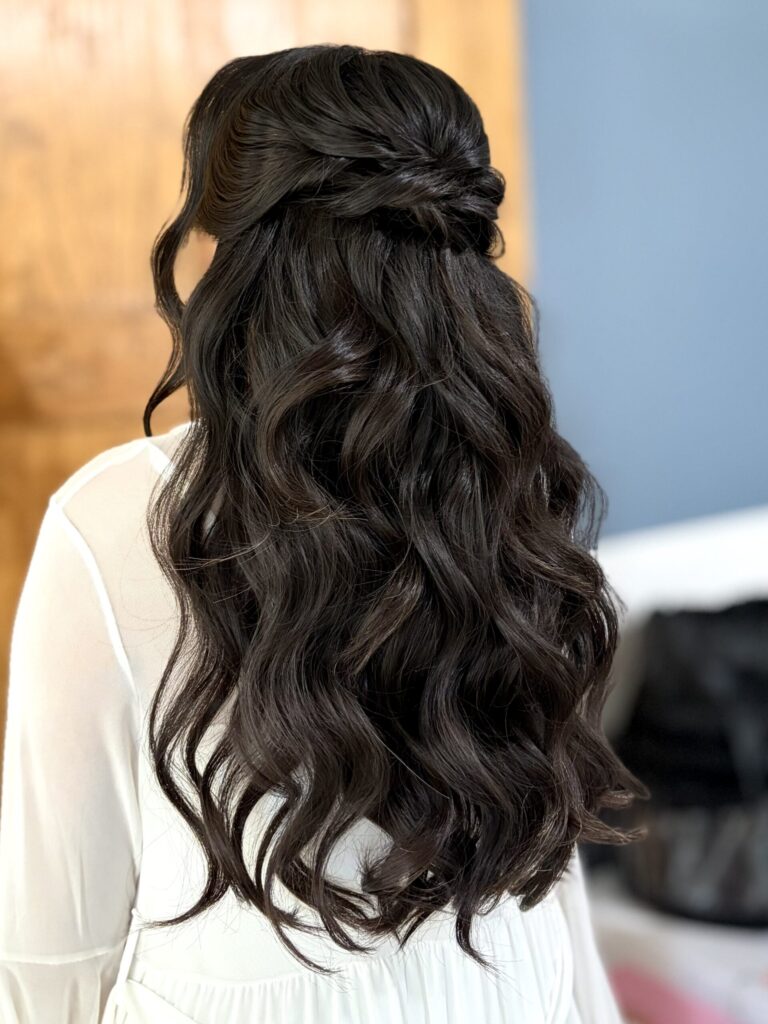 Bridal model with a long black half-up half-down curly style. Hair is shiny and glowy with loose curls, and a waterfall braid. Styled by Jaya Ronquillo at the Belleza Styles studio in Ann Arbor Michigan. 