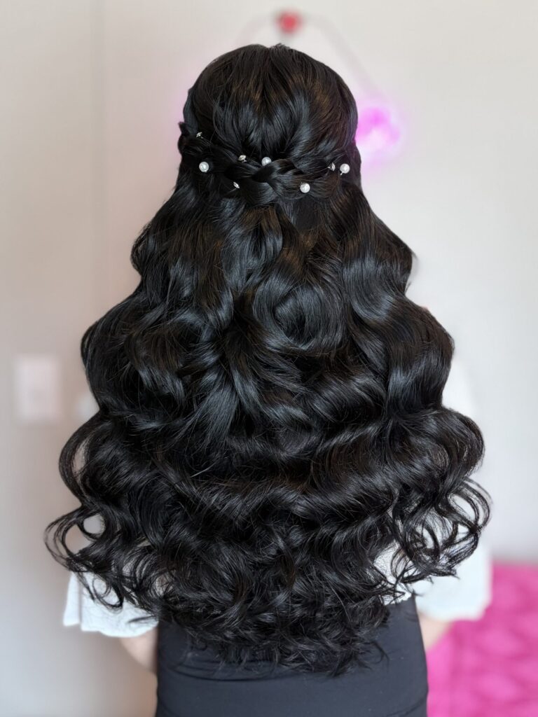 Bridal model with a black half-up half-down style with fluffy curls and a braid around the crown. Adorned in the back by pearl ornaments.  Styled by Jaya Ronquillo at the Belleza Bridal studio in Ann Arbor Michigan.