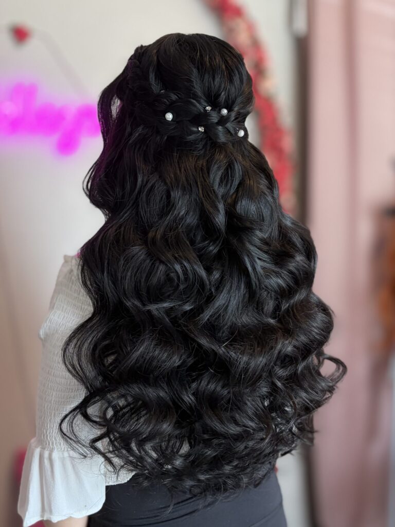 Bridal model with a black half-up half-down style with fluffy curls and a braid around the crown. Adorned in the back by pearl ornaments.  Styled by Jaya Ronquillo at the Belleza Bridal studio in Ann Arbor Michigan.