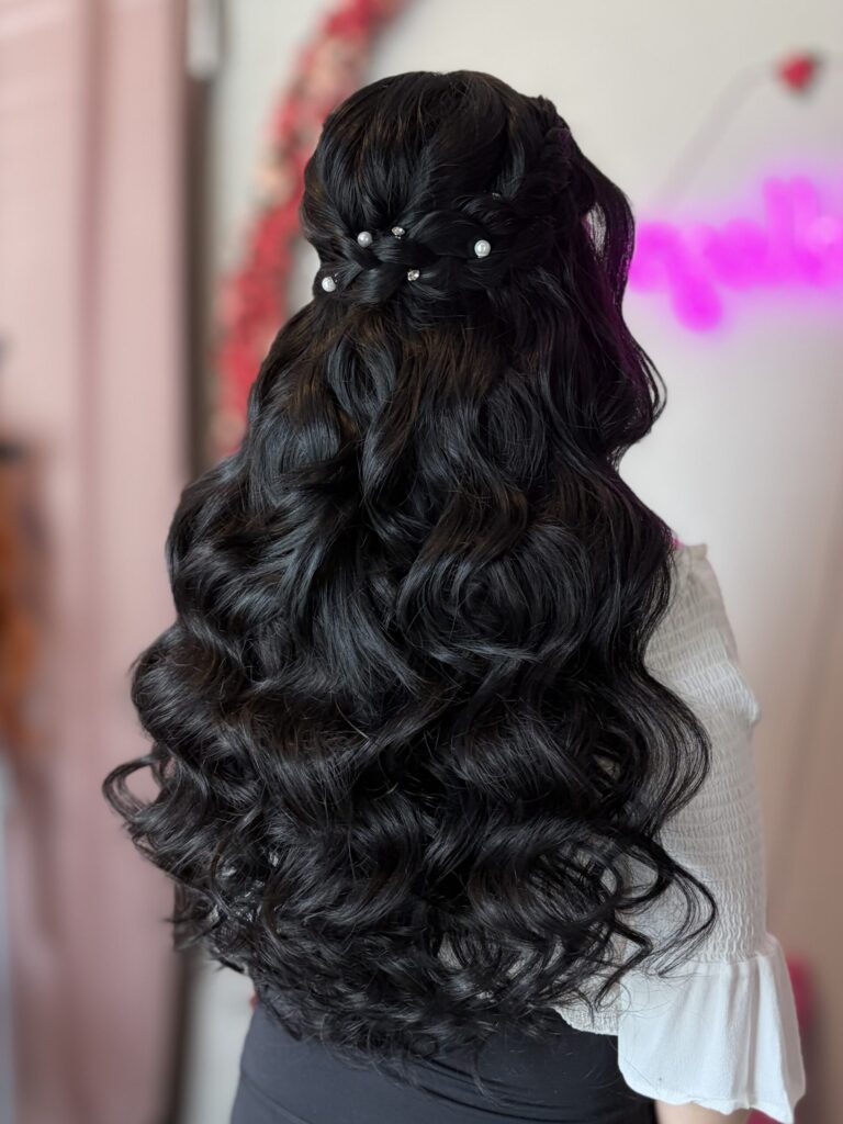 Bridal model with a black half-up half-down style with fluffy curls and a braid around the crown. Adorned in the back by pearl ornaments.  Styled by Jaya Ronquillo at the Belleza Bridal studio in Ann Arbor Michigan.