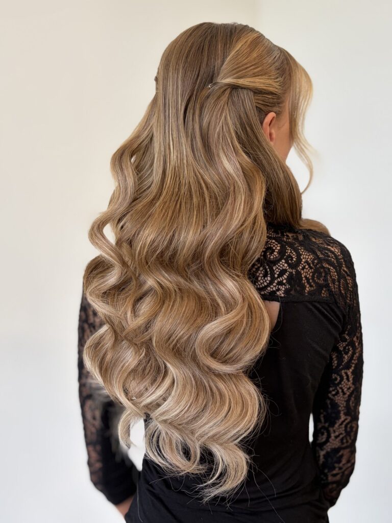 Bridal model with a dirty blonde half-up half-down style with loose curls, face framing, and pinned back curls. Styled by Jaya Ronquillo at the Belleza Bridal studio in Ann Arbor Michigan.