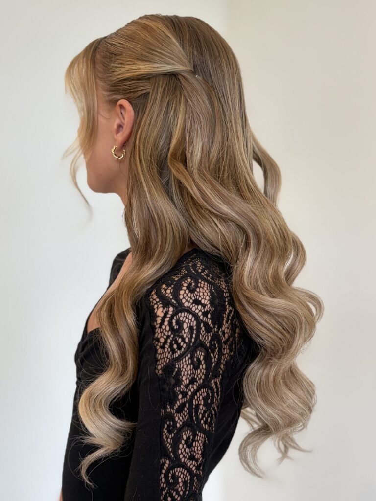 Bridal model with a dirty blonde half-up half-down style with loose curls, face framing, and pinned back curls. Styled by Jaya Ronquillo at the Belleza Bridal studio in Ann Arbor Michigan.